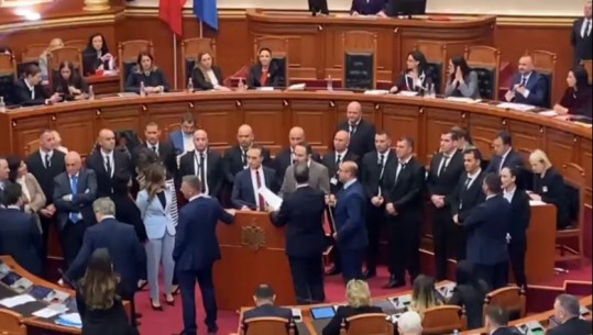 VIDEO/ Me bidonë dhe duar i bien tavolinave, deputetët e opozitës bllokojnë foltoren! Sajmir Korreshi shfaqet me bilbil në dorë