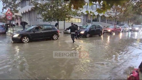 Durrës/ Mbushen me ujë rrugët pranë stadiumit, prindërit marrin fëmijët në krah për t’u kaluar rrugën (VIDEO)