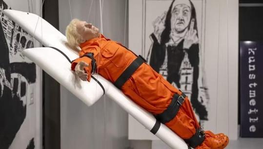 I lidhur në një kryq dhe me uniformën e të burgosurit, ekspozohet në Zvicër skulptura prej dylli e Donald Trump  (VIDEO)